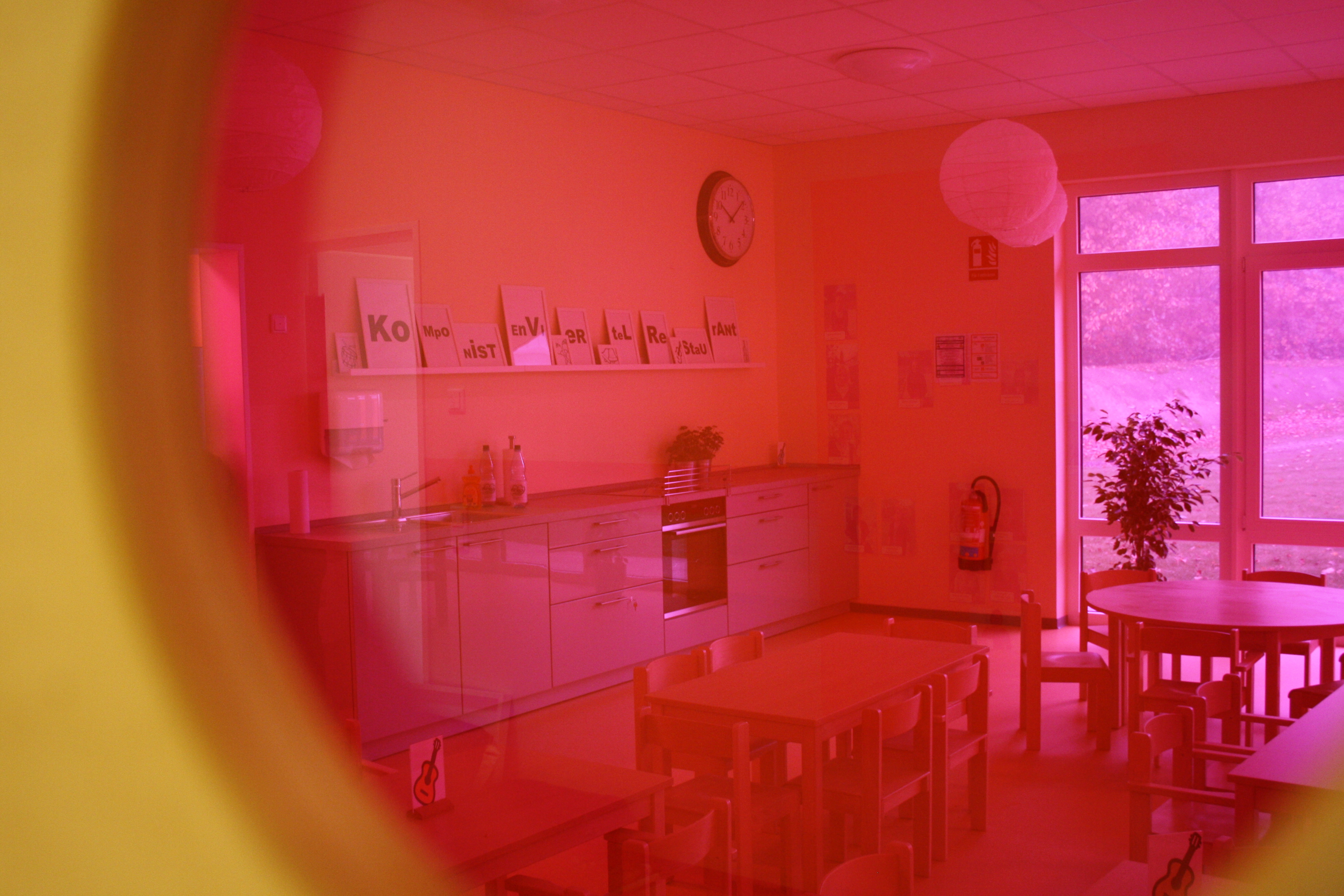 Foto: Blick durch ein pinkes Fenster in das Kinder-Café