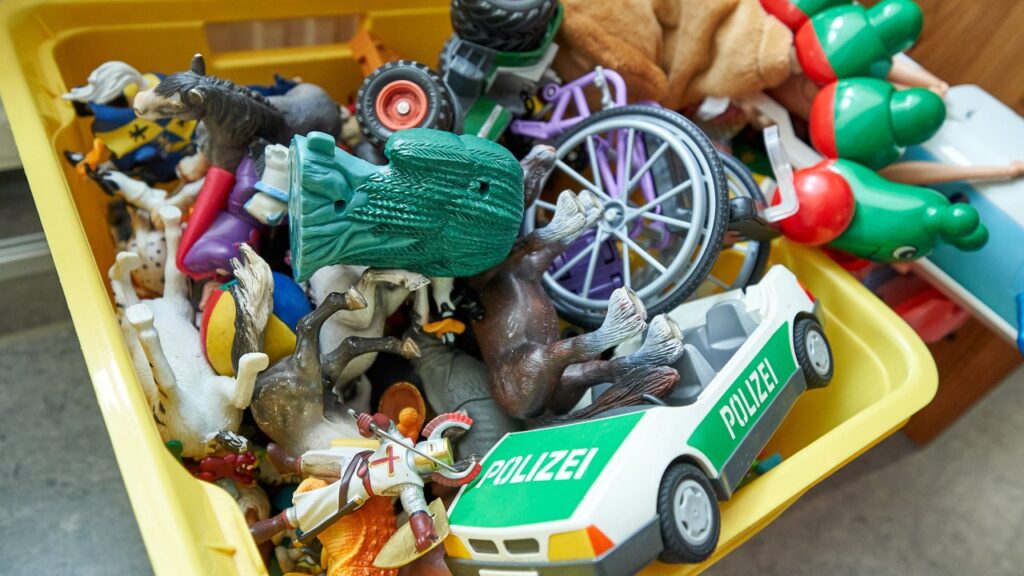 Eine Kiste mit verschiedenen Spielfiguren und einem Playmobil Polizei Auto