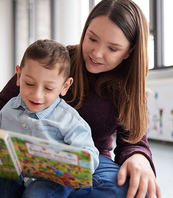 Eine Frau liest zusammen mit einem Kind in ihrem Schoß ein Buch